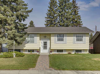 Charming home with a welcoming facade, featuring a well-maintained lawn and a brick pathway leading to the front door.