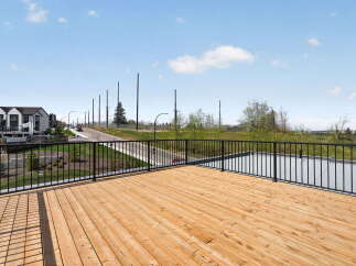 Enjoy stunning views from this modern property featuring a spacious wooden deck and sleek black railings.