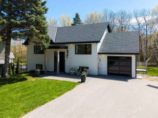This stunning property boasts a modern design with a sleek, white exterior and a dark, contrasting roof.