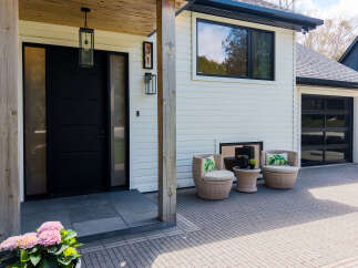 This stunning property boasts a modern exterior with a sleek black door and a welcoming porch.