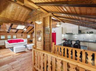 Step into this charming chalet-style home, boasting a warm and inviting interior with exposed wooden beams and paneling.