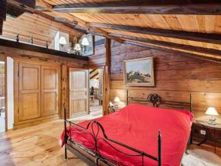 Experience rustic charm in this cozy bedroom featuring exposed wooden beams and walls.