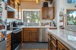 This charming kitchen boasts warm wooden cabinetry and a stainless steel dishwasher, creating a welcoming atmosphere.