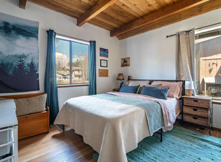 This cozy bedroom features a rustic wooden ceiling and hardwood floors, creating a warm and inviting atmosphere.