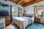 This cozy bedroom features a rustic wooden ceiling and hardwood floors, creating a warm and inviting atmosphere.