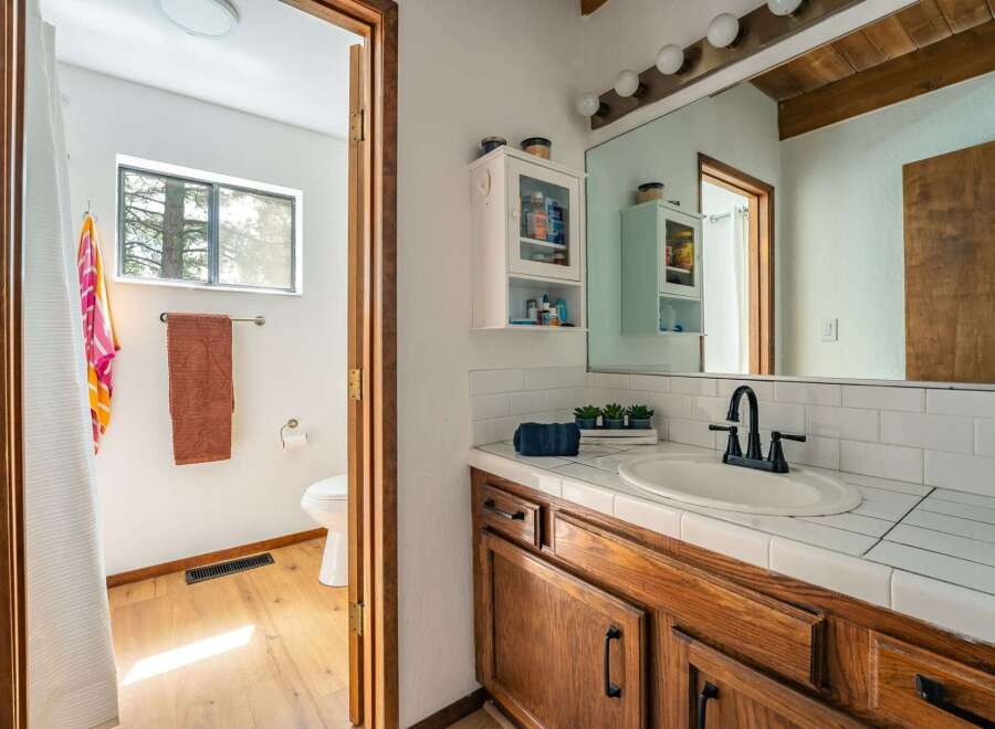 Step into this charming bathroom, featuring a warm wooden vanity and a bright, inviting atmosphere.