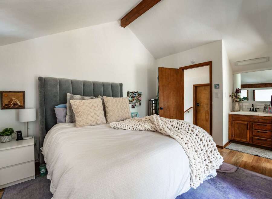 Step into this inviting bedroom, featuring a plush, upholstered headboard and a cozy, oversized knit throw.