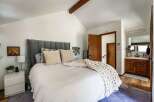 Step into this inviting bedroom, featuring a plush, upholstered headboard and a cozy, oversized knit throw.