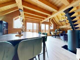 Experience luxury living in this stunning chalet, featuring a spacious open-plan design with exposed wooden beams and large windows that offer breathtaking mountain views.