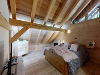 Discover the charm of this cozy bedroom featuring a unique wooden ceiling and walls, creating a warm and inviting atmosphere.