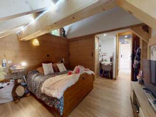 Discover the charm of this cozy bedroom, featuring a warm wooden interior and a comfortable bed.