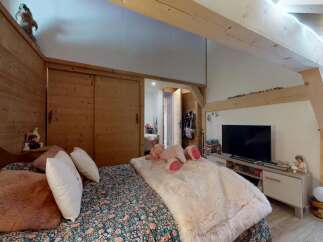 Discover the charm of this cozy bedroom, featuring a warm wooden interior and a comfortable bed.