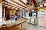 Step into rustic elegance with this stunning kitchen, featuring exposed wooden beams and a charming stone wall.