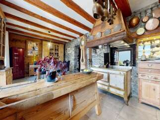 Step into rustic elegance with this stunning kitchen, featuring exposed wooden beams and a charming stone wall.
