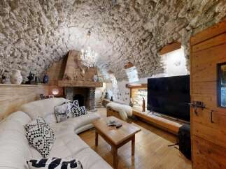 Step into rustic elegance with this stunning property! Featuring a unique stone-walled interior, a cozy fireplace, and a luxurious white leather sofa, this home offers a blend of comfort and style.