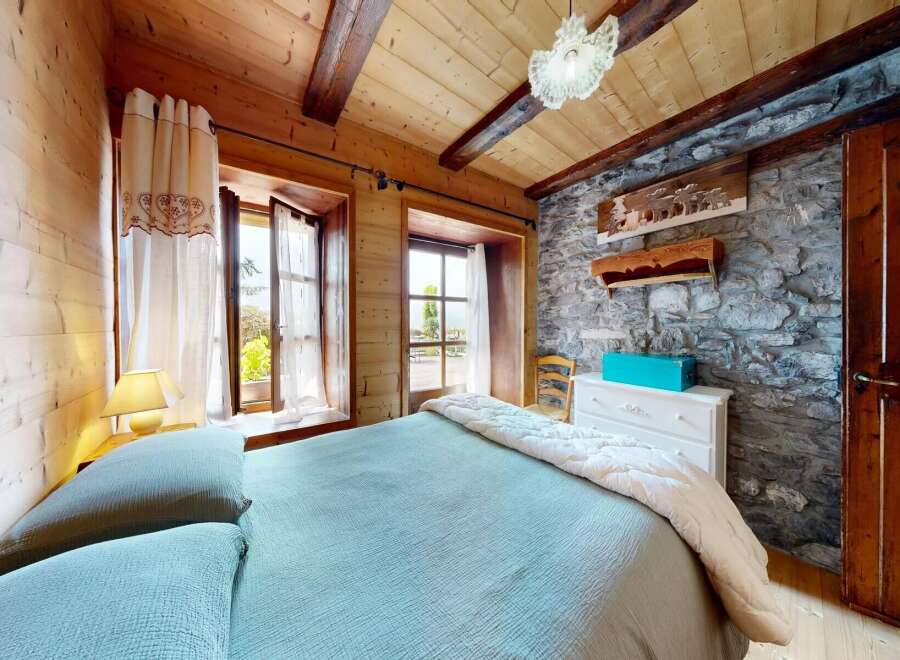 Discover the charm of this cozy bedroom, featuring a rustic stone wall and wooden accents that create a warm and inviting atmosphere.