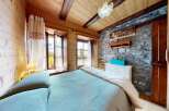 Discover the charm of this cozy bedroom, featuring a rustic stone wall and wooden accents that create a warm and inviting atmosphere.
