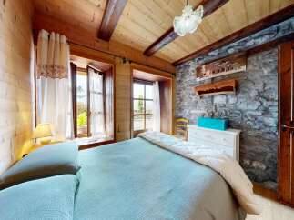 Discover the charm of this cozy bedroom, featuring a rustic stone wall and wooden accents that create a warm and inviting atmosphere.
