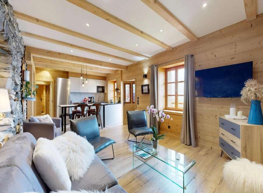 Experience the charm of this stunning property, featuring a beautifully designed living space with exposed wooden beams and a cozy stone wall.