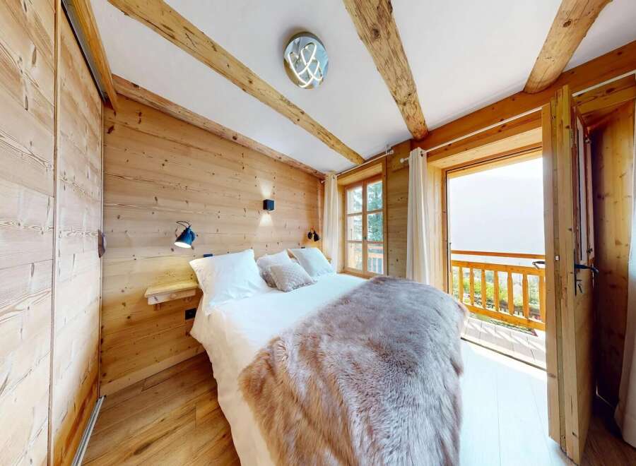 Experience the charm of this cozy bedroom featuring a rustic wooden interior and a plush, inviting bed.