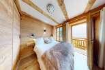 Experience the charm of this cozy bedroom featuring a rustic wooden interior and a plush, inviting bed.