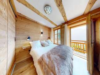 Experience the charm of this cozy bedroom featuring a rustic wooden interior and a plush, inviting bed.