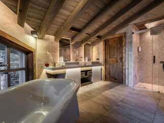 Indulge in luxury within this stunning bathroom, featuring a rustic wooden ceiling and elegant tile flooring.