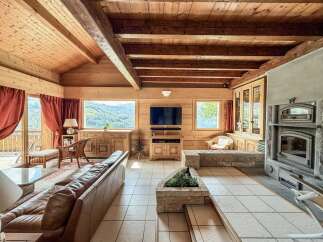 Experience the warmth of this stunning wooden chalet, boasting a cozy living room with a fireplace and exposed beams.