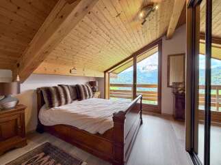 Experience the charm of this stunning bedroom with its rustic wooden ceiling and breathtaking mountain views.