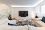 Experience modern living in this stunning property, featuring a spacious living room with a sleek, wall-mounted TV.