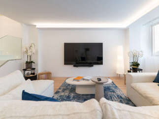 Experience modern living in this stunning property, featuring a spacious living room with a sleek, wall-mounted TV.