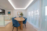 This stunning dining room features a modern design with an oval wooden table and plush blue velvet chairs, creating an inviting space for gatherings.