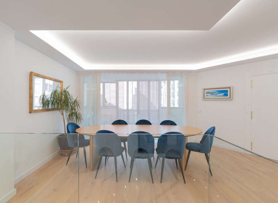 This elegant dining room features a large wooden table surrounded by stylish blue chairs, perfect for hosting gatherings.