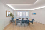 This elegant dining room features a large wooden table surrounded by stylish blue chairs, perfect for hosting gatherings.