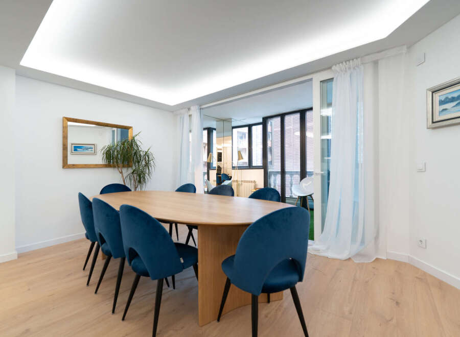 This stunning dining room features a modern oval table surrounded by stylish blue chairs, creating an inviting space for gatherings.