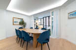 This stunning dining room features a modern oval table surrounded by stylish blue chairs, creating an inviting space for gatherings.