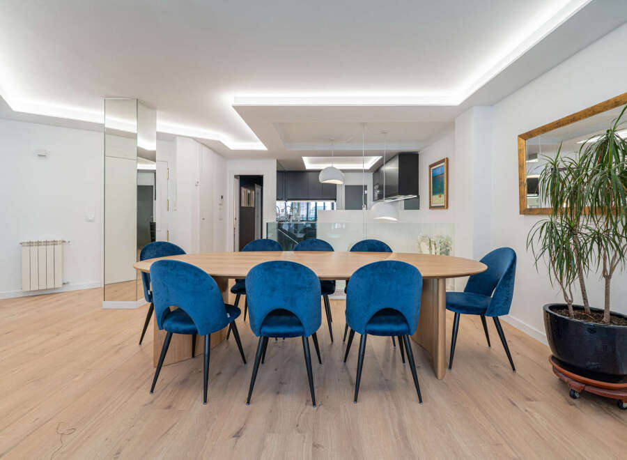 This stunning dining room features a modern design with a large wooden table and stylish blue velvet chairs.