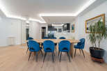 This stunning dining room features a modern design with a large wooden table and stylish blue velvet chairs.