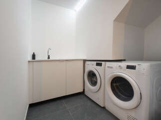 Discover the convenience of this modern laundry room, featuring a sleek design and efficient appliances.