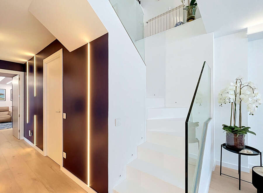 Experience modern luxury in this stunning home featuring a sleek, open-concept staircase with glass railings and ambient LED lighting.