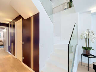 Experience modern luxury in this stunning home featuring a sleek, open-concept staircase with glass railings and ambient LED lighting.
