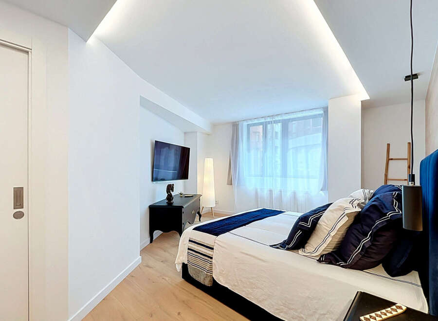 Experience modern comfort in this beautifully appointed bedroom, featuring a plush king-size bed adorned with elegant navy and white linens.
