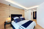 Experience modern luxury in this master bedroom, featuring a stunning wood-paneled accent wall and sleek, integrated LED lighting.