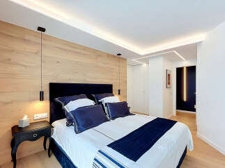 Experience modern luxury in this master bedroom, featuring a stunning wood-paneled accent wall and sleek, integrated LED lighting.