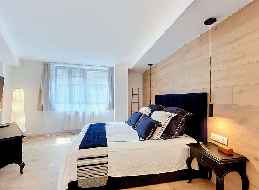 Experience modern comfort in this beautifully appointed bedroom, featuring a plush king-size bed with luxurious navy blue accents and a striking wooden accent wall.
