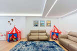 This spacious living area is perfect for families, featuring two comfortable leather sofas and a vibrant blue abstract rug.