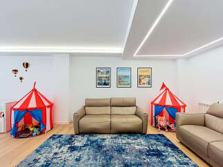 This spacious living area is perfect for families, featuring two comfortable leather sofas and a vibrant blue abstract rug.