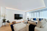 Experience modern luxury in this spacious living room, featuring a sleek wall-mounted TV and ambient recessed lighting.