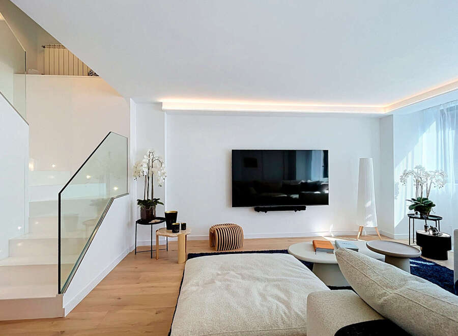 Experience modern luxury in this stunning living space, featuring a sleek entertainment center with a large flat-screen TV and ambient lighting.