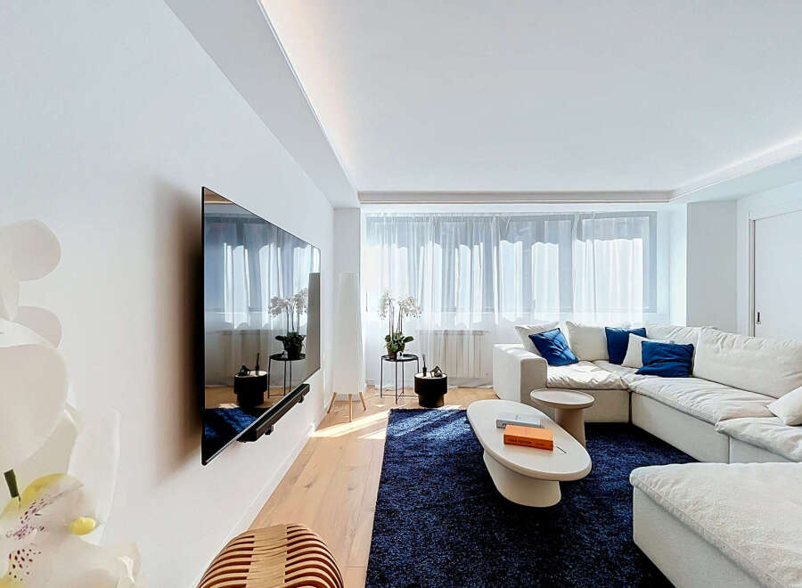 Experience modern living in this bright and airy living room, featuring a large sectional sofa adorned with plush blue accent pillows.